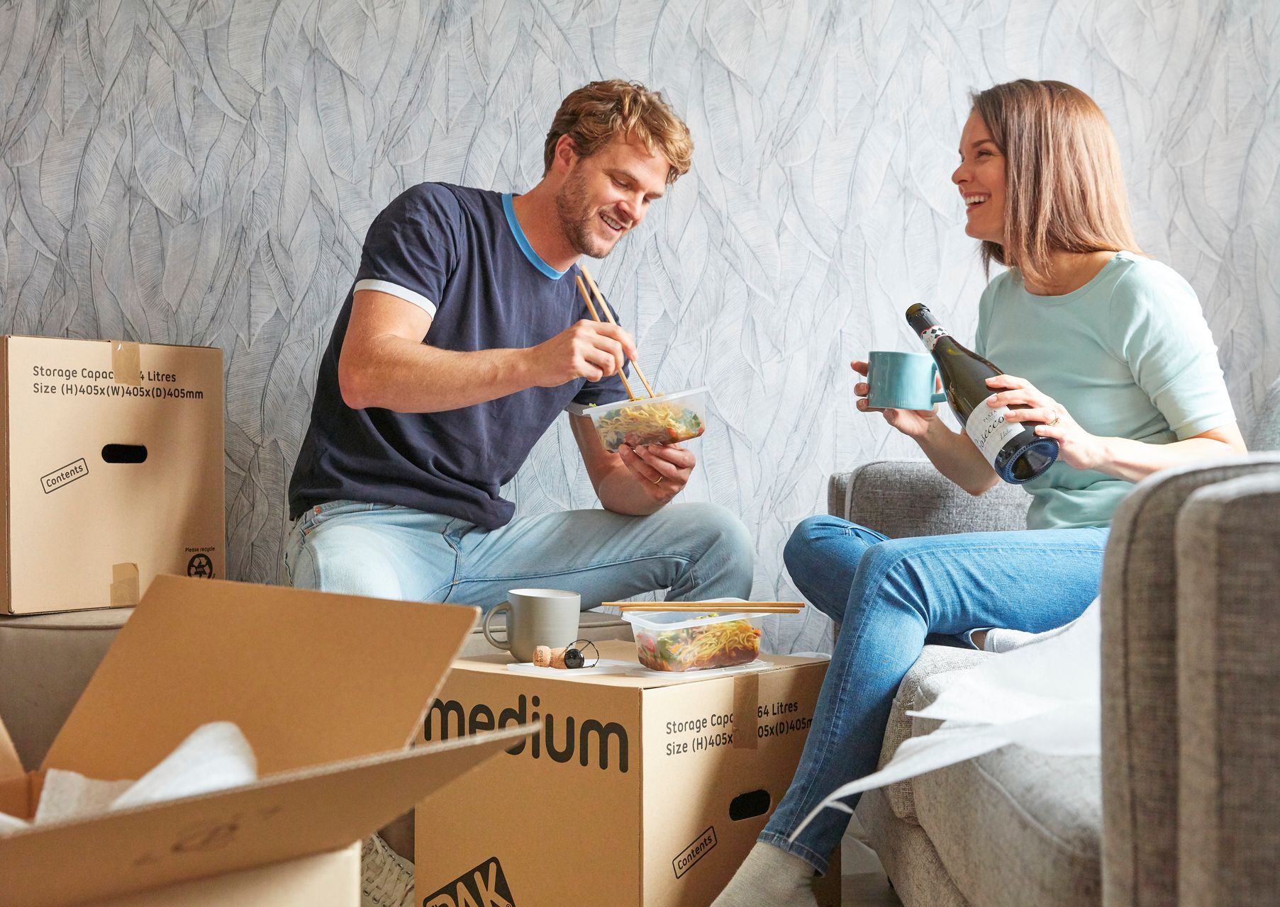 A woman and a man have lunch at a table made of a cardboard box in a show home